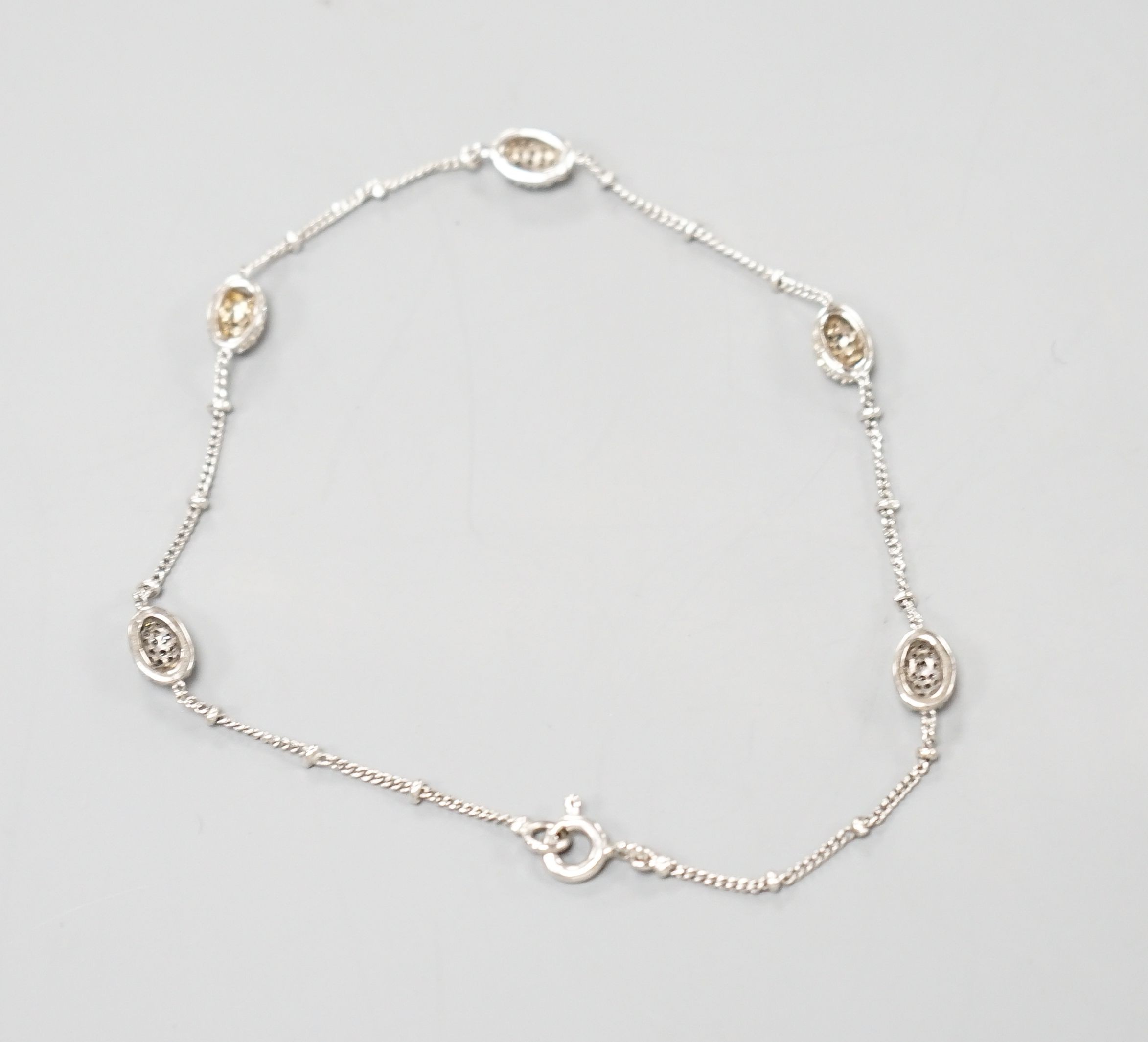 A modern 750 white metal and diamond chip set demi lune link bracelet, 19cm